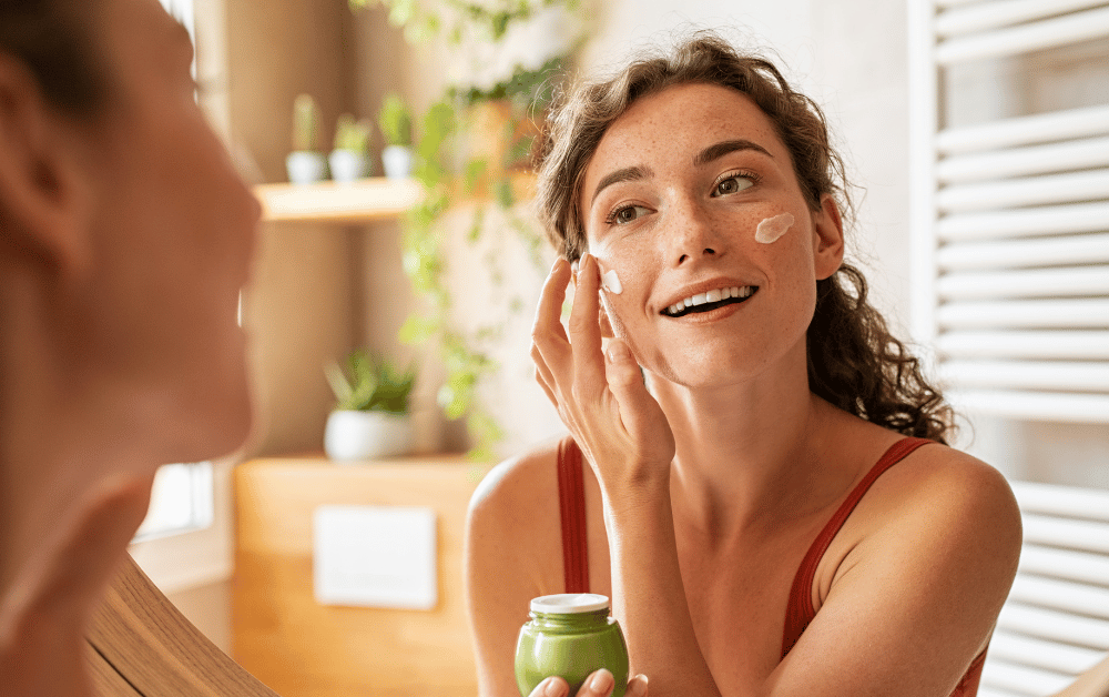 A woman applying skincare in her bathroom, showing the benefits of a skincare routine for mental health and self-care.