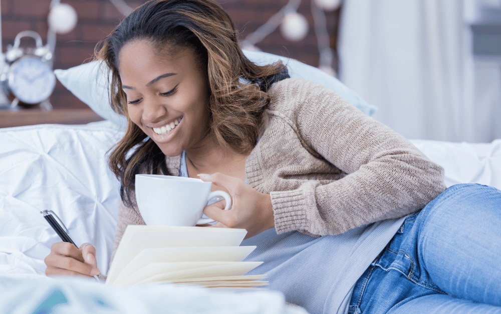 Woman drinking coffee while journaling for mental health in a cozy setting, promoting self-care and mindfulness.