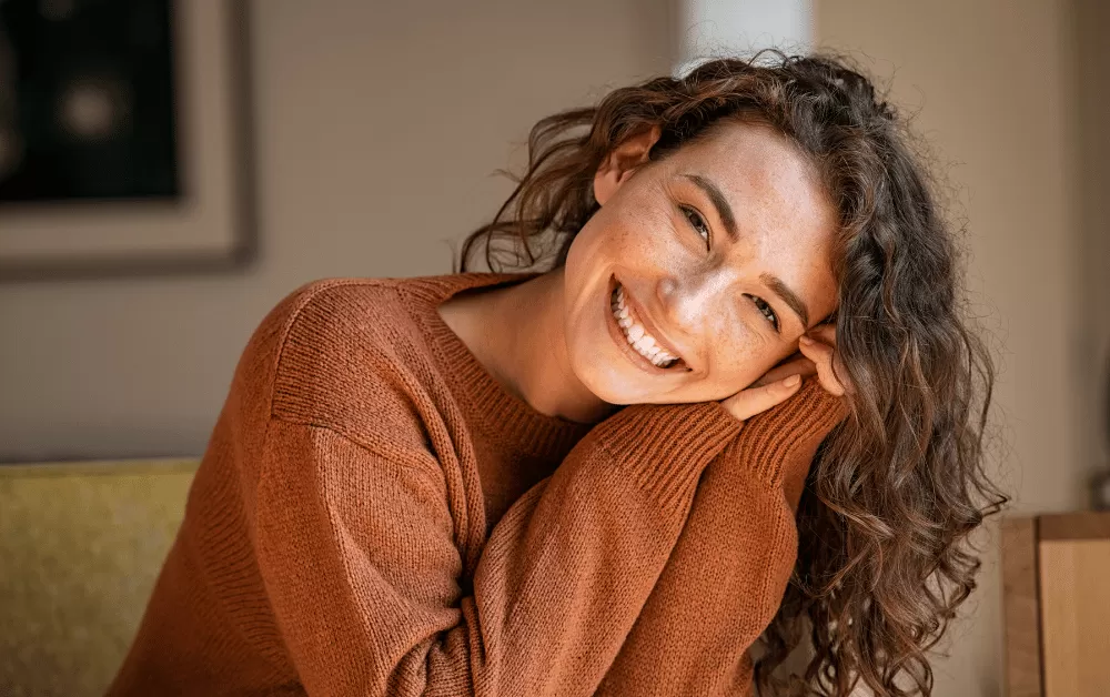 Unlock Your True Potential with 5 Tips on How to Glow Up Mentally! Happy woman sitting on sofa at home.