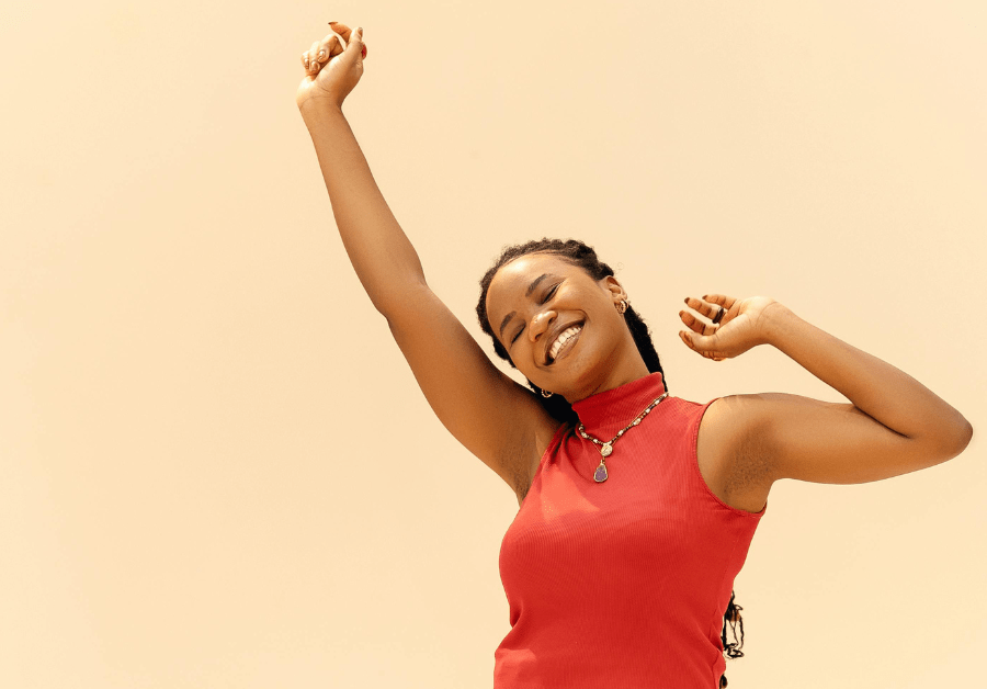 A happy woman dancing joyfully in the sunlight, radiating confidence and self-love — a perfect representation of how to glow up from the inside out.