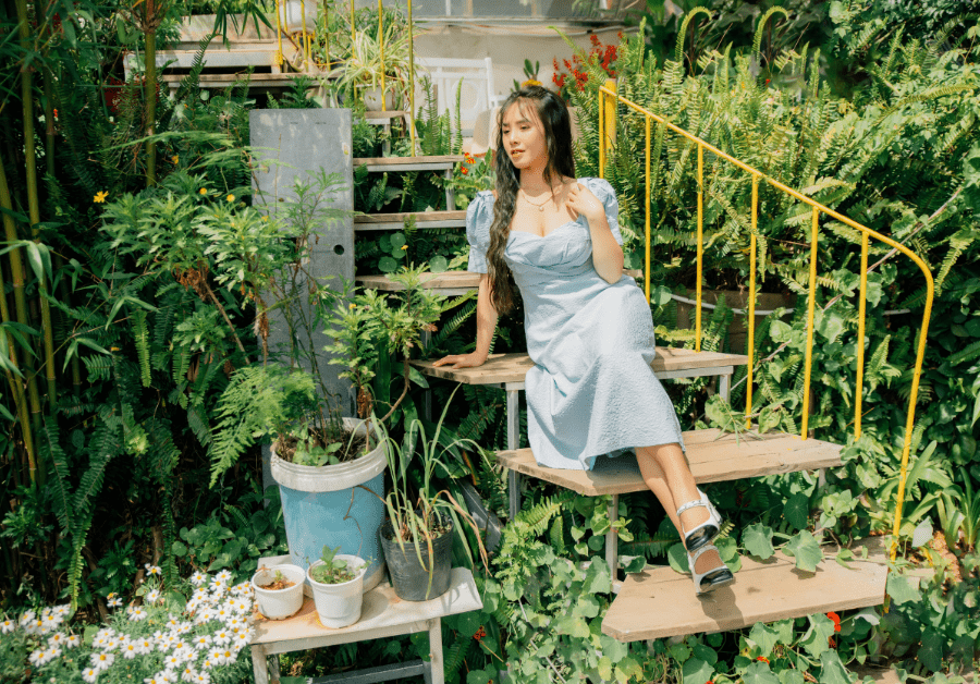 A woman sitting on garden stairs enjoying a peaceful moment, surrounded by plants and greenery, representing outdoor ideas for home and mindful living.