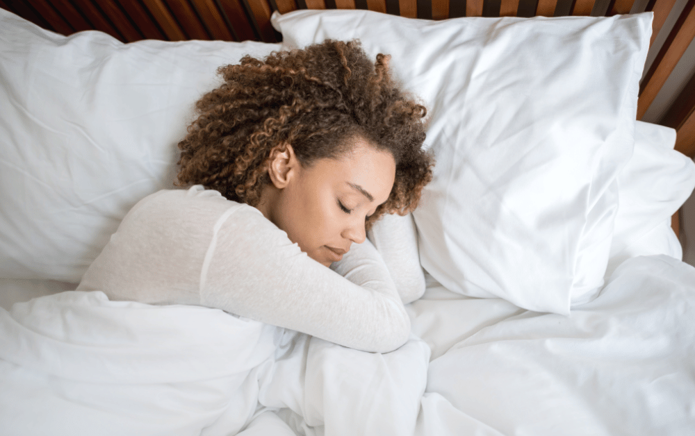 Woman peacefully sleeping in bed, representing the connection between sleep hygiene and mental health.