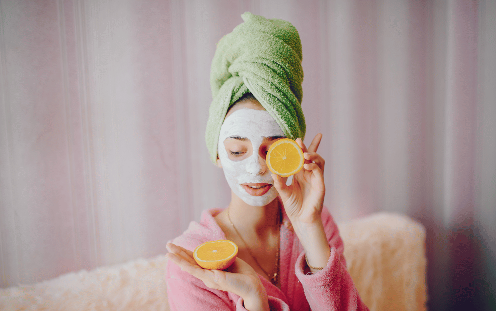 Woman practicing face masks self care in a pink gown, relaxing with a nourishing facial treatment.