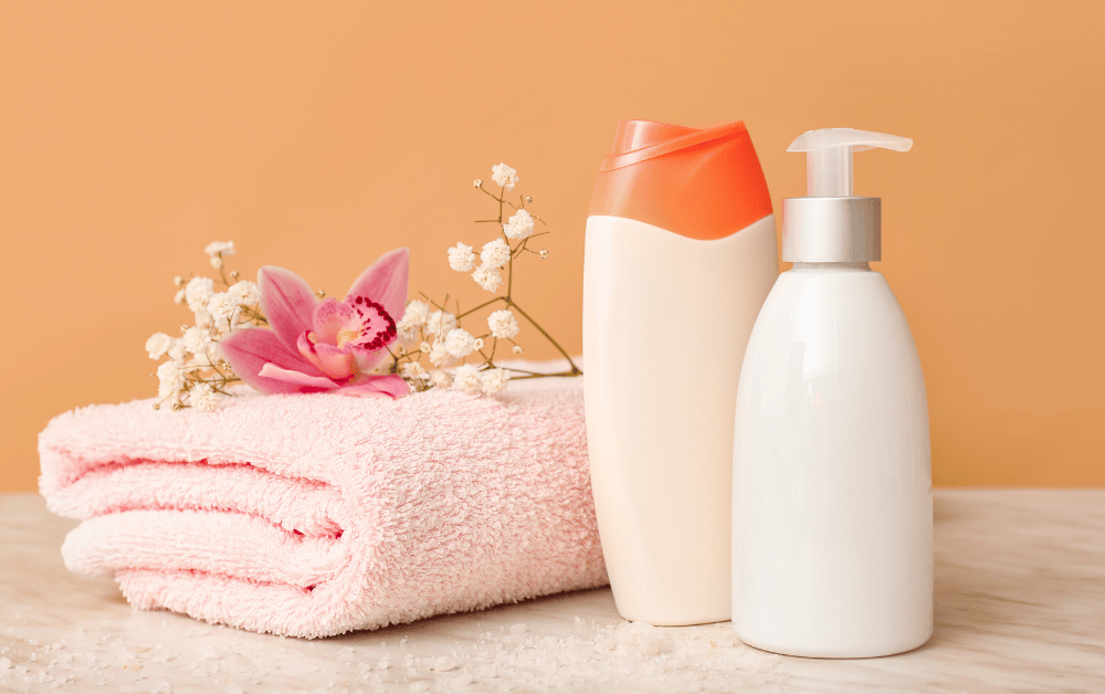 Cleanest body wash with lotion next to a folded towel and fresh flowers on a cute background.