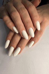 Close-up of white almond-shaped nails with a clean glossy finish, featuring an elegant and timeless manicure perfect for chic New Year’s nails.