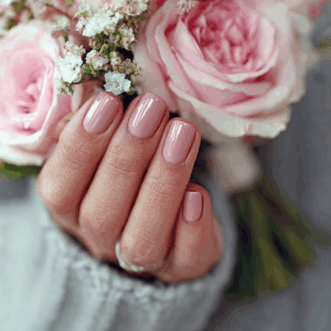 Soft pink nails paired with delicate flowers, styled as romantic Valentine’s Day nails.