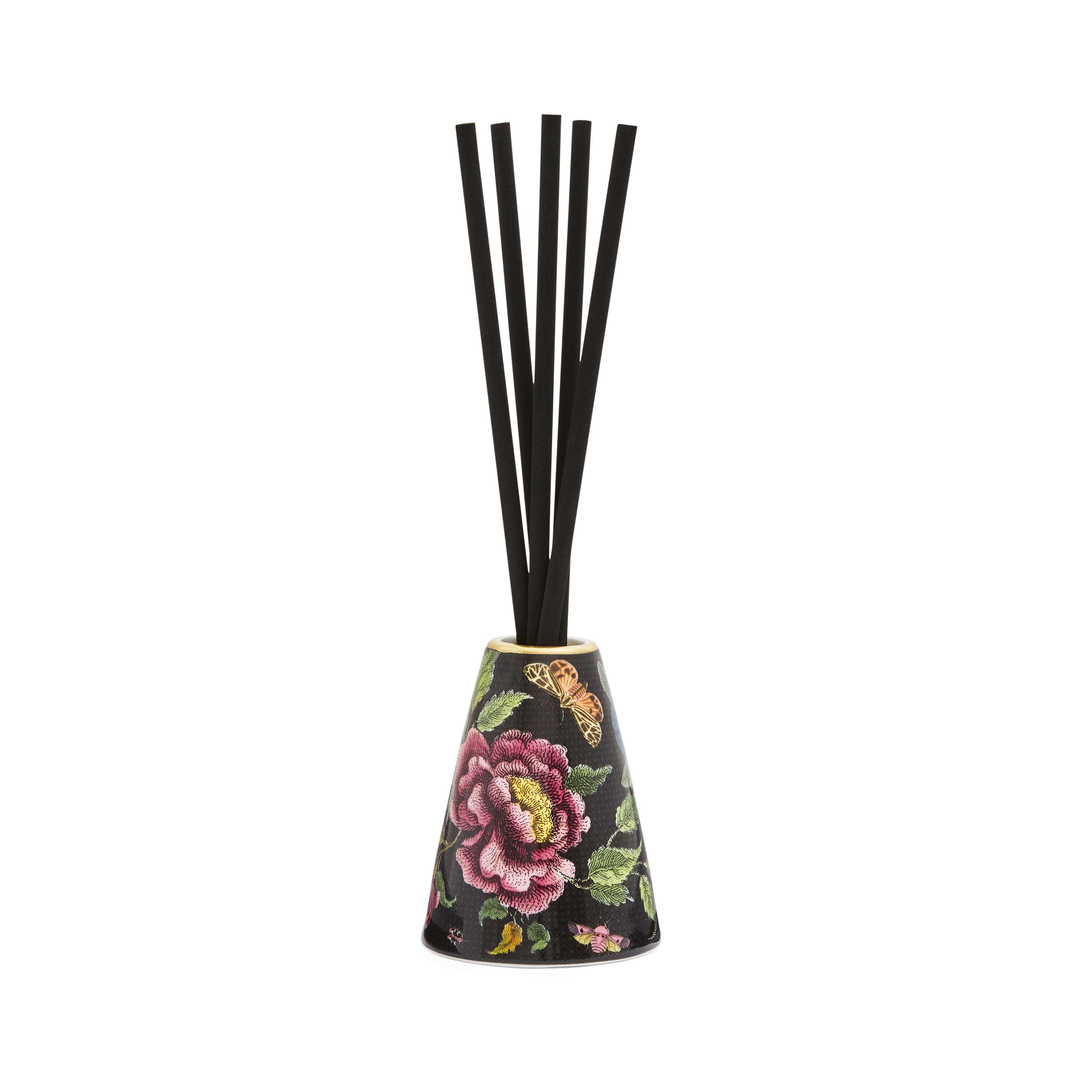 Creatures of Curiosity Cream Dark Floral Reed Diffuser in a cream-colored vessel with dark floral detailing, displayed with fragrance reeds for home diffusers.