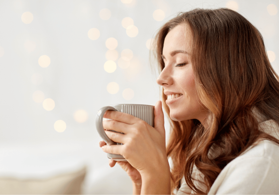 A woman recovering from burnout smiling while enjoying a cup of tea in a calm setting, representing recover from burnout, burnout recovery, self-care, and stress relief.